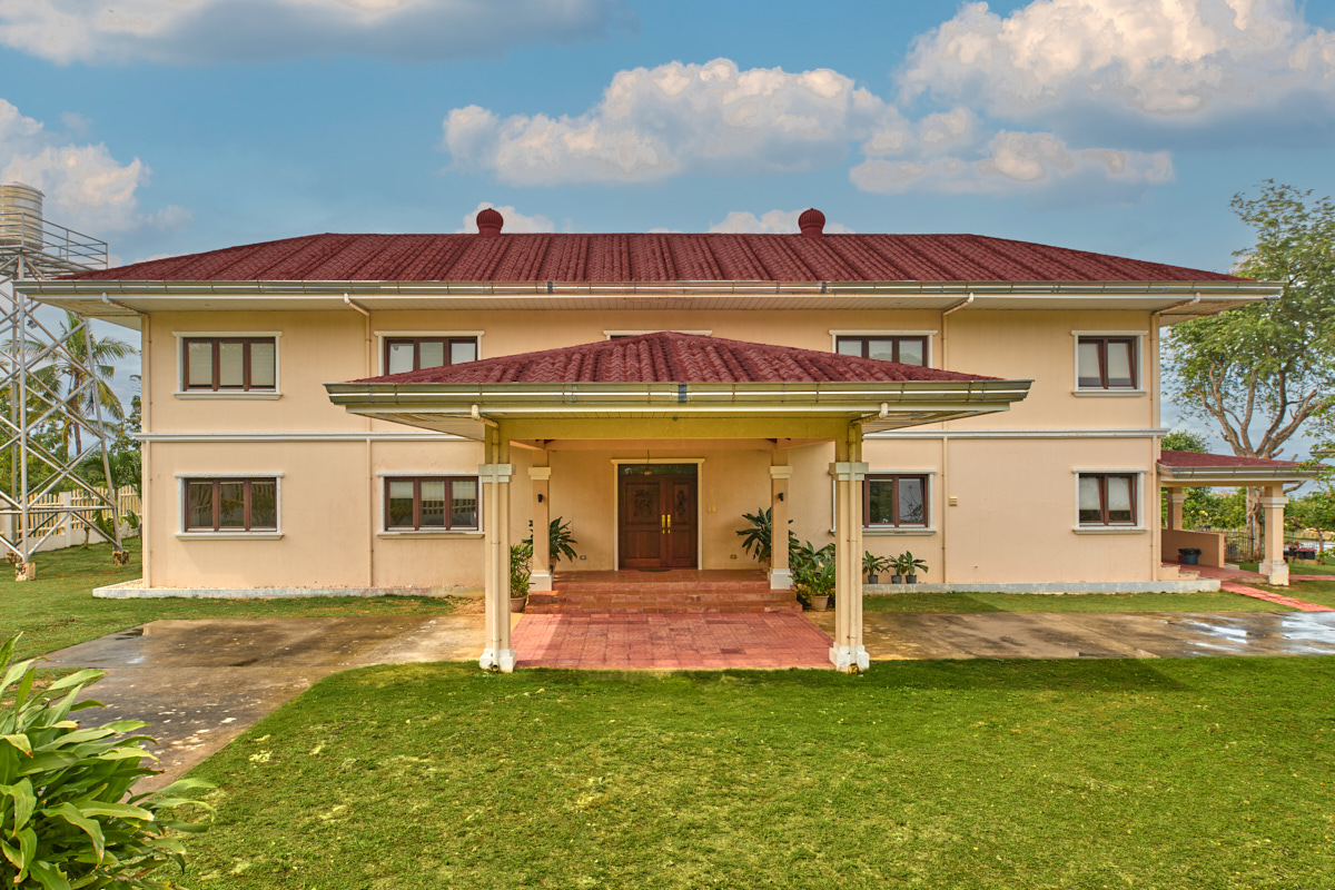 Front of the two-storey residence with covered entrance, red tiled roof and lawn